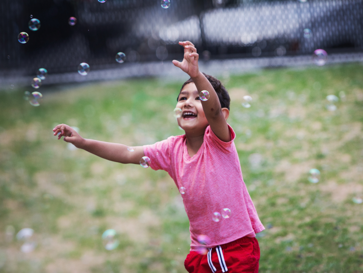 girl playing outside with bubbles