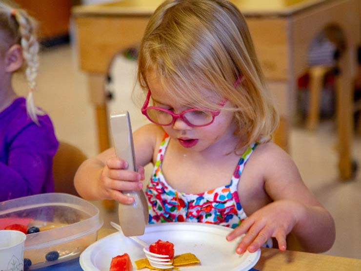Preschooler measuring food onto her plate