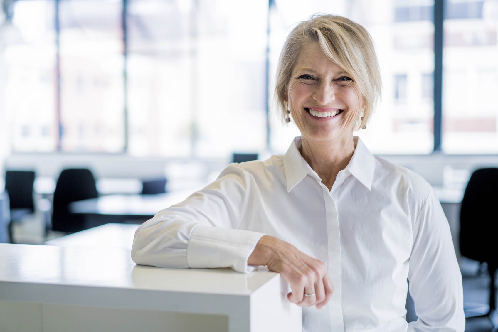 An older business woman leaning on her desk.