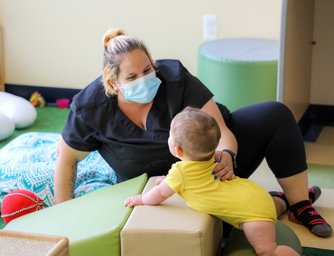 daycare teacher wearing a mask while teaching in the infant classroom