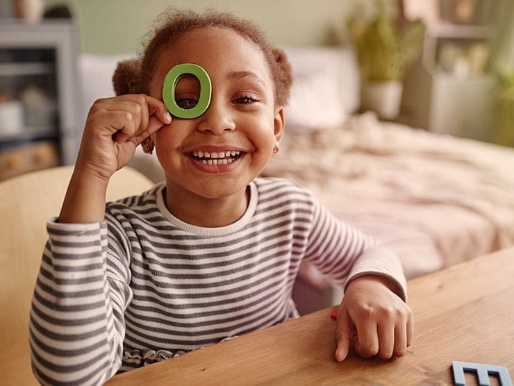 Little girl holding playing with toy letters at home 