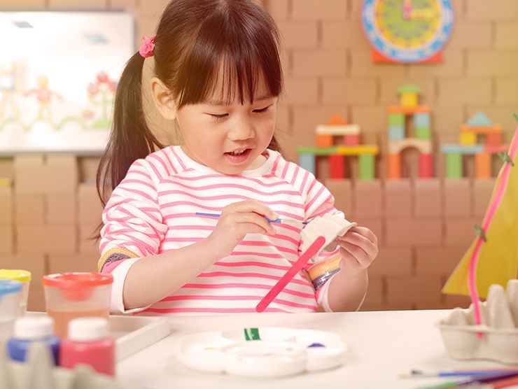 Preschooler doing an art project with recycled egg cartons at day care 