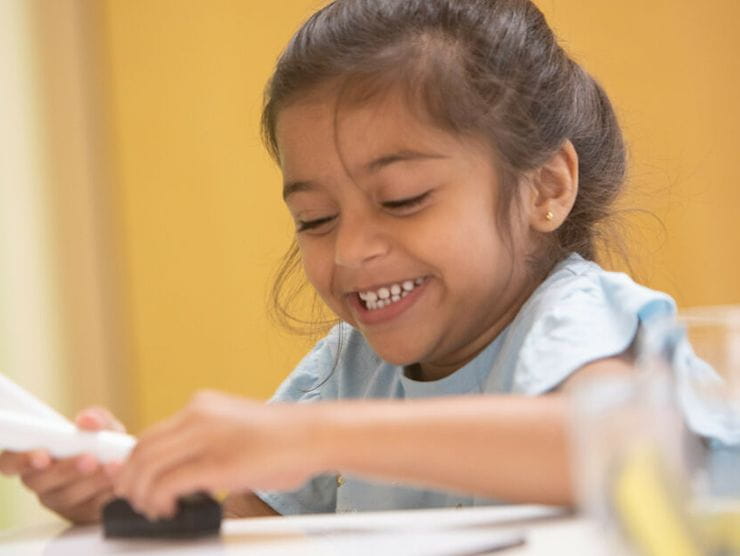 Girl smiling while developing a time capsule at childcare center 