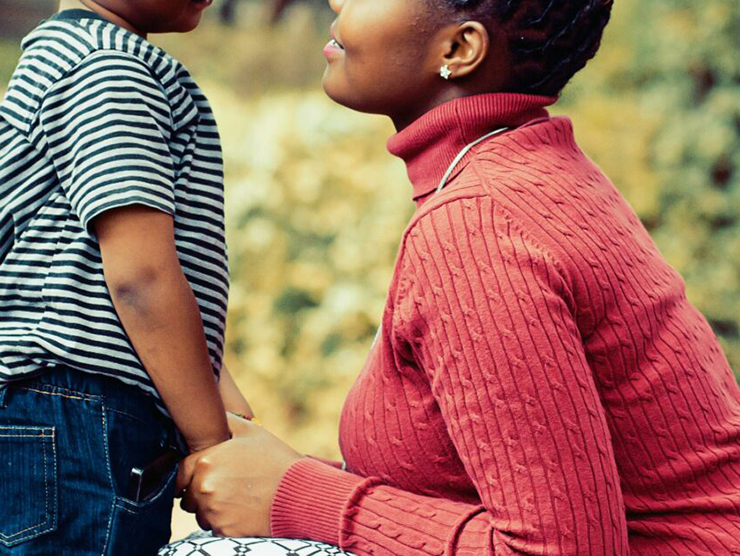 Little boy holding hands with his mother and smiling which represents a positive relationship with an adult 