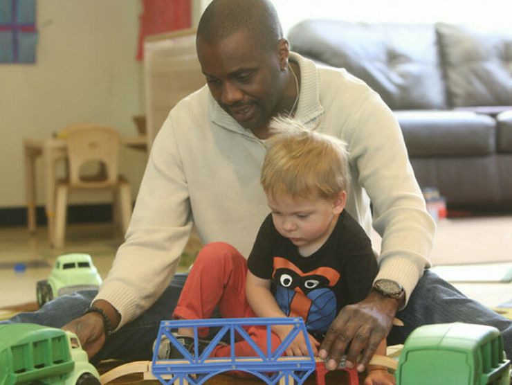 Toddler and teacher playing with trains to promote the development of print and alphabet   