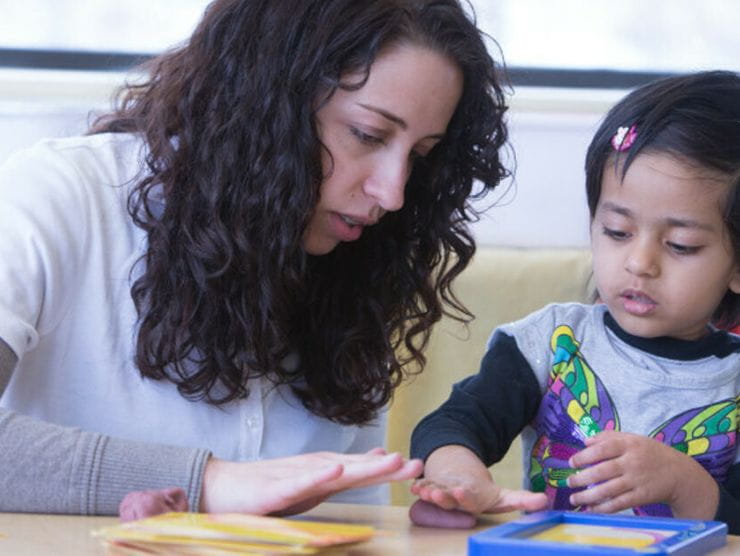 Child at daycare using play doh to create shapes 