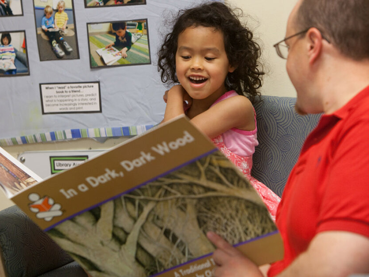 Teacher and toddler reading a book together at day care 