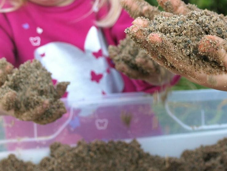 Toddlers playing with a bucket of sand at day care 