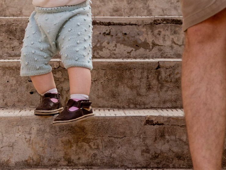 Dad holding baby's hand while going down the stairs  