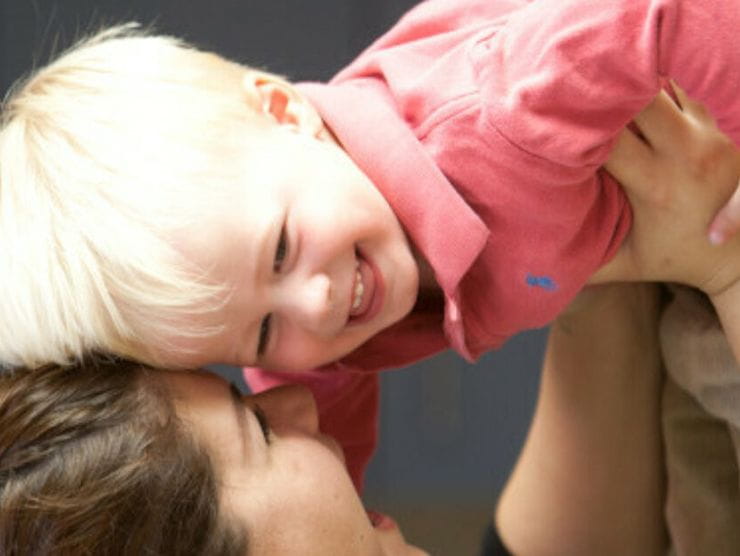 Adult holding toddler while laughing at day care