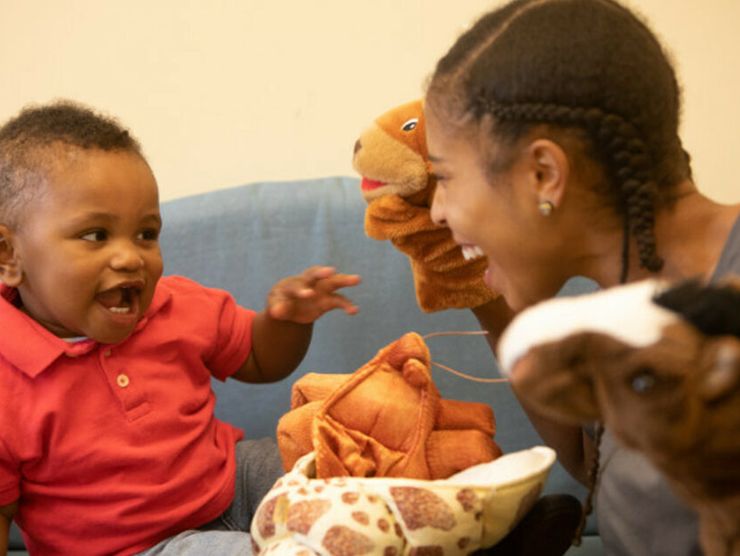 Teacher and toddler playing with a variety of sock puppet animals