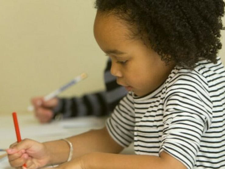 Toddler using pencil to write on paper at daycare 