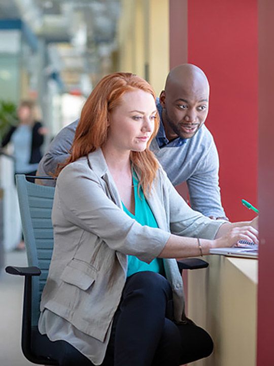 A man and woman looking at a computer screen