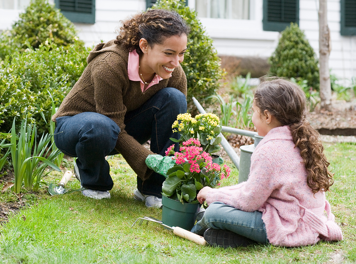 Mother smiling and playing with daughter in garden outside