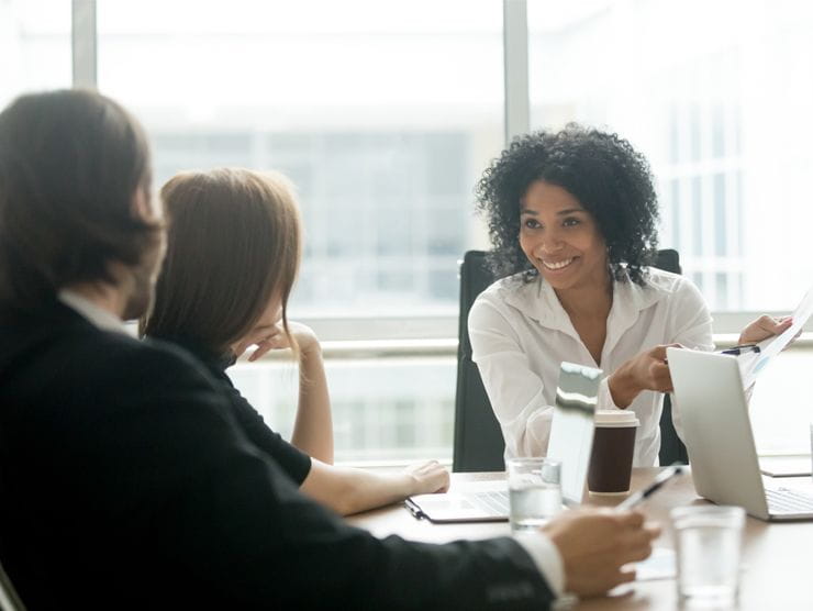 woman in office talking to colleagues at desk 