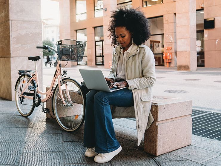 Woman working on laptop next to bicycle