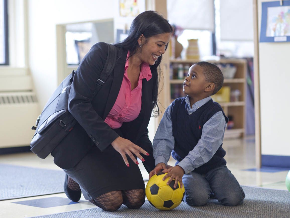 A working mother and her son playing with a soccer ball at a child care center