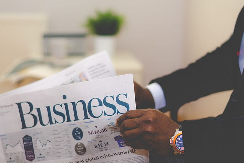 Man holding a newspaper that says "Business"