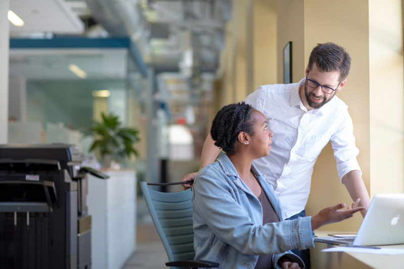 Gen Z employee showing her manager something on her computer