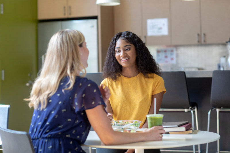 Woman mentoring a younger colleague at lunch