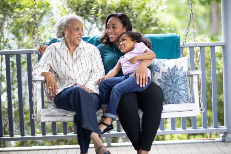 Adult caregiver with a young child caring for her sick, elderly relative