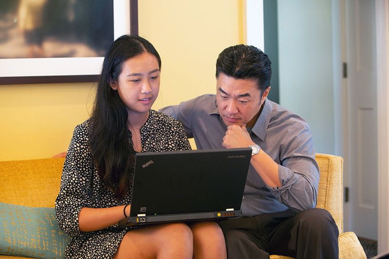 Working dad and teenage daughter looking at college tuition prices