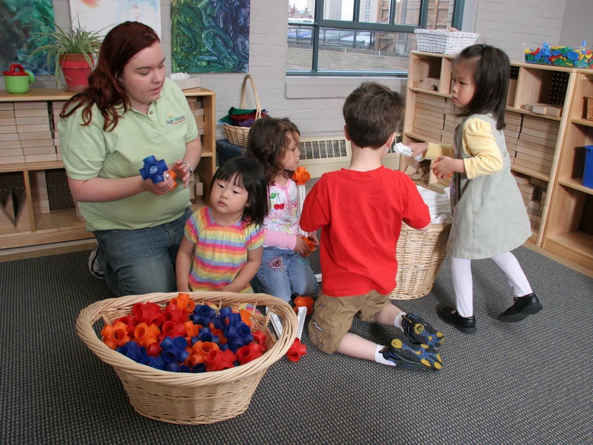 A group of children putting toys away in their toy bin