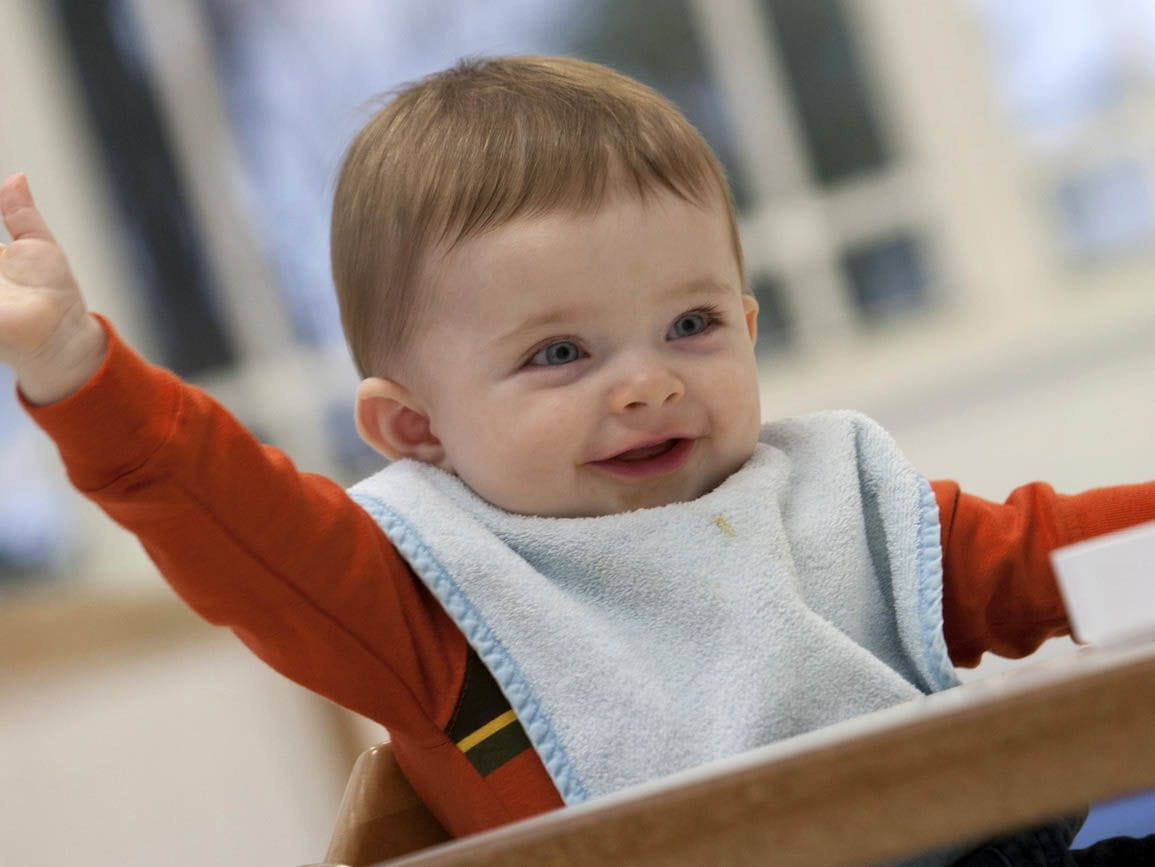 A young child eating at a high chair