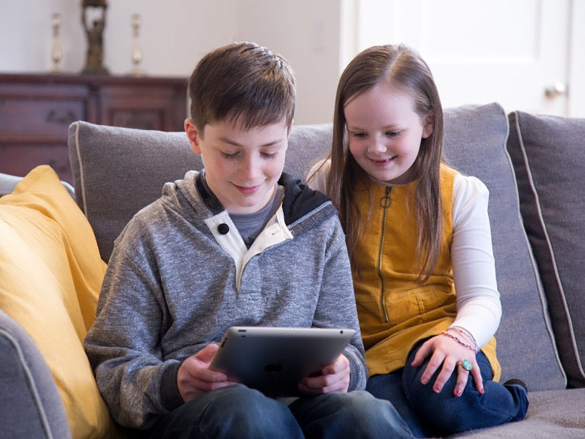 Two young children using a tablet at home