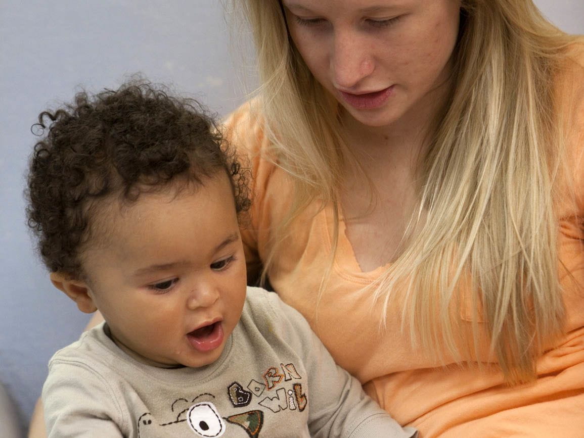 A child care teacher reading to an infant