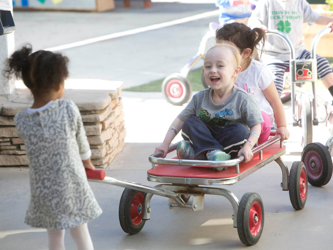 A child pulling two others in a wagon