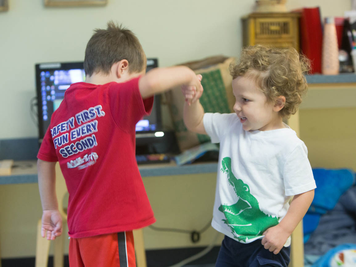 Kindergarten-aged boy shaking hands with preschool boy