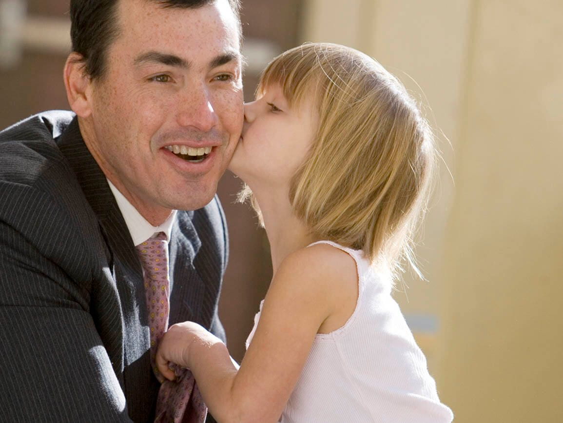 A dad getting a kiss from his daughter