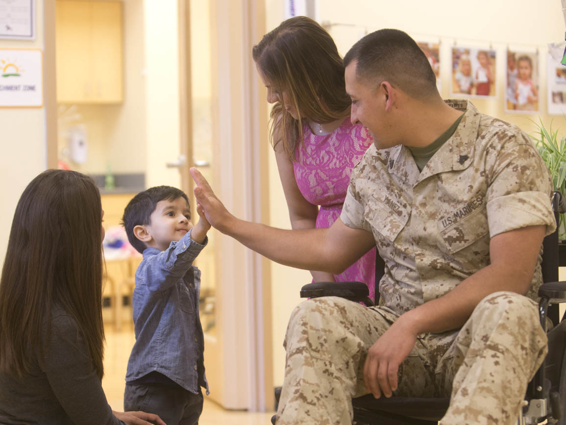 A child-fiving a soldier in a wheelchair