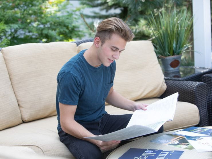 High school student reading through college brochures