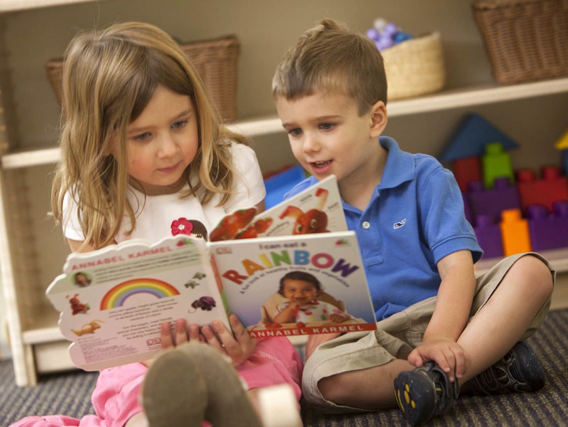 Young sister and brother reading together on the floor