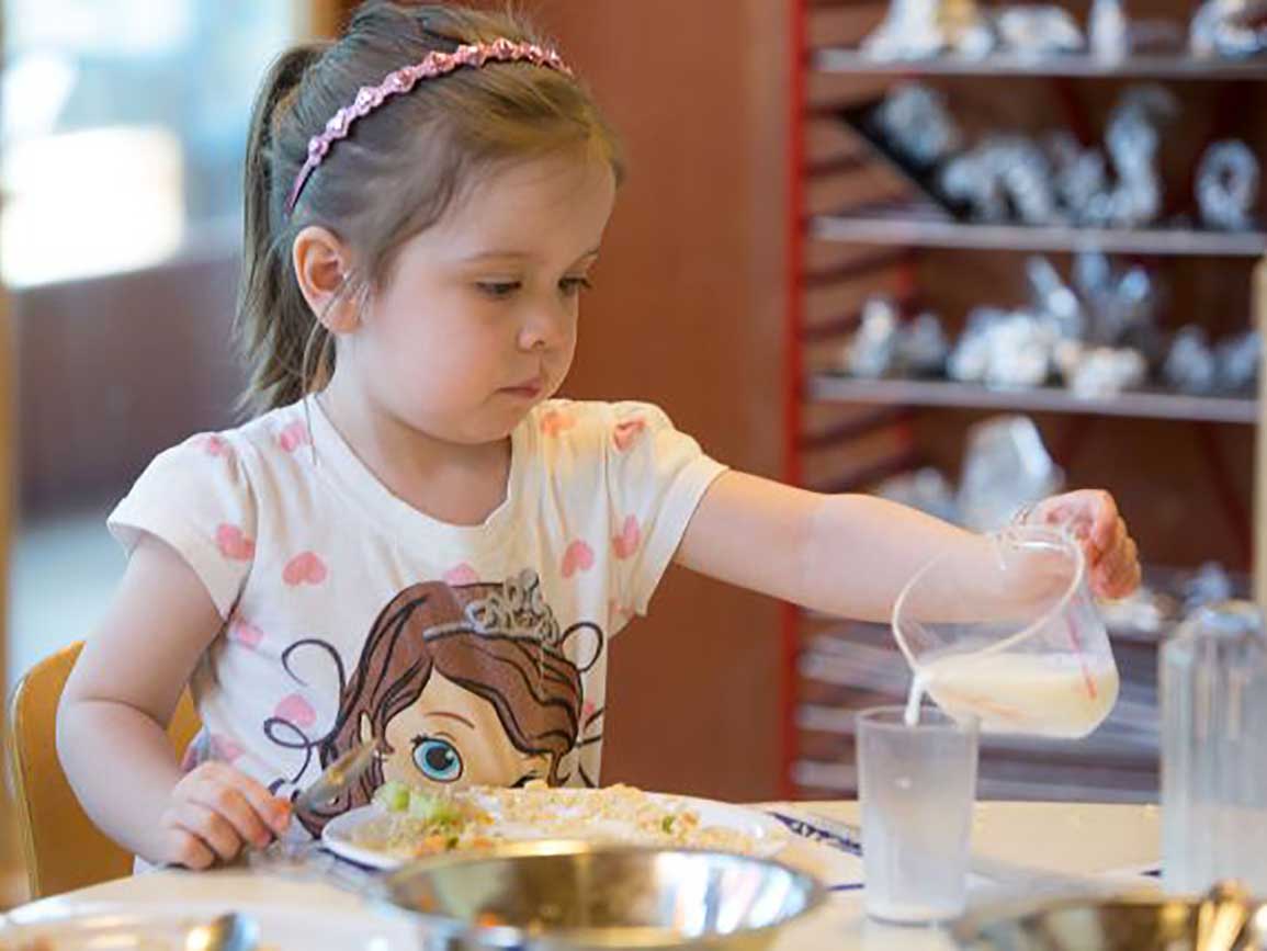 Preschool girl pouring milk