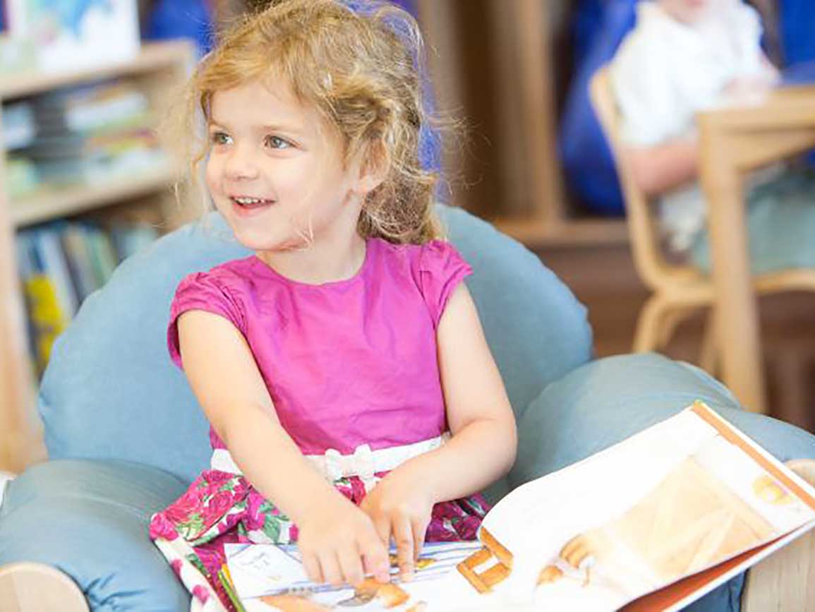 Preschool girl reading a book