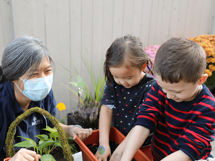 Parent with mask on overlooking children playing in garden