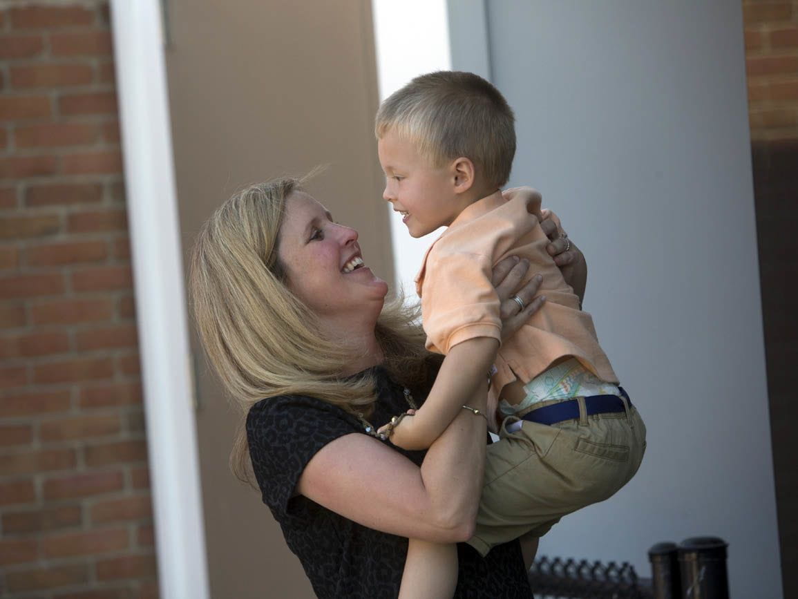 A mother picking up her toddler son