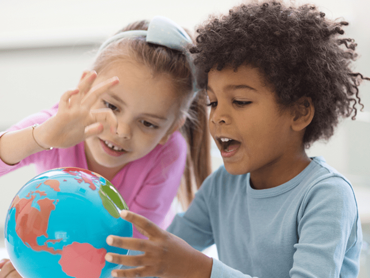 Two children looking at a globe