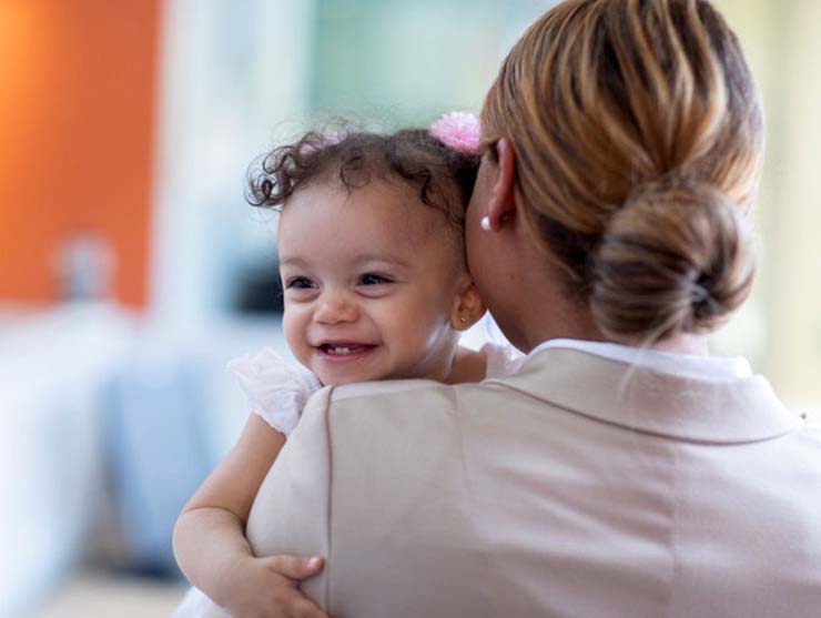 Working mom holding her toddler daughter