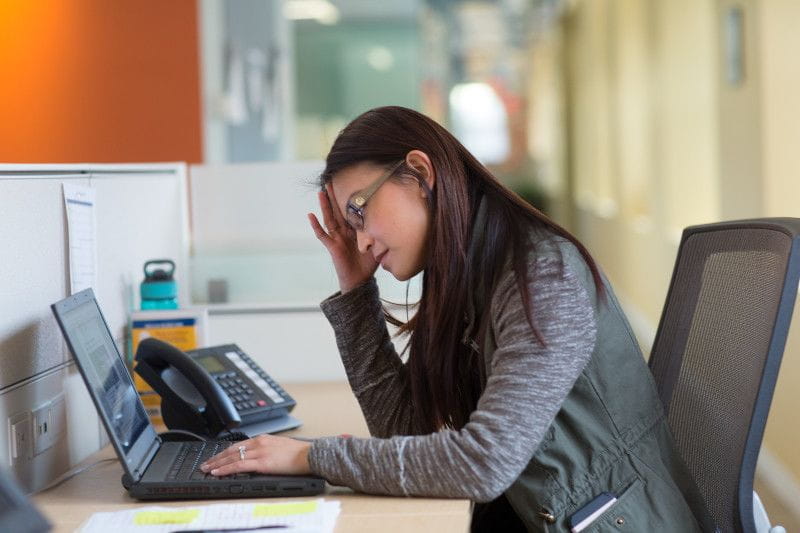 Young woman looking at her computer with her head in her hands